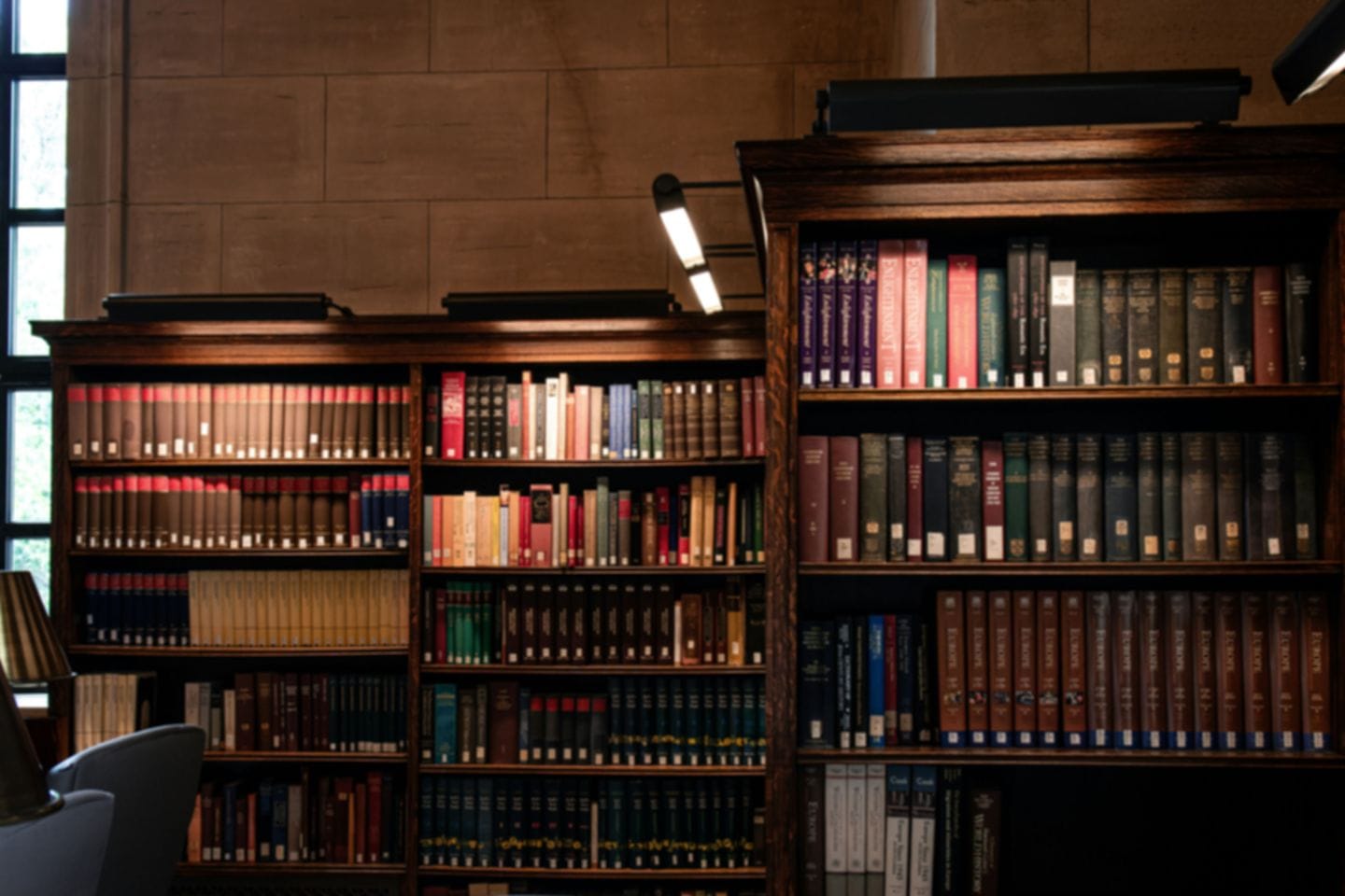 Holzregale mit gebundenen Zeitschriftenbänden in einer Bibliothek, darüber eine Leselampe